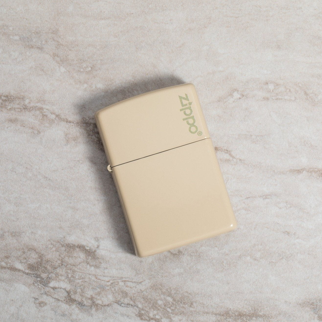 Lifestyle image of Classic Flat Sand Zippo Logo laying on a marble surface